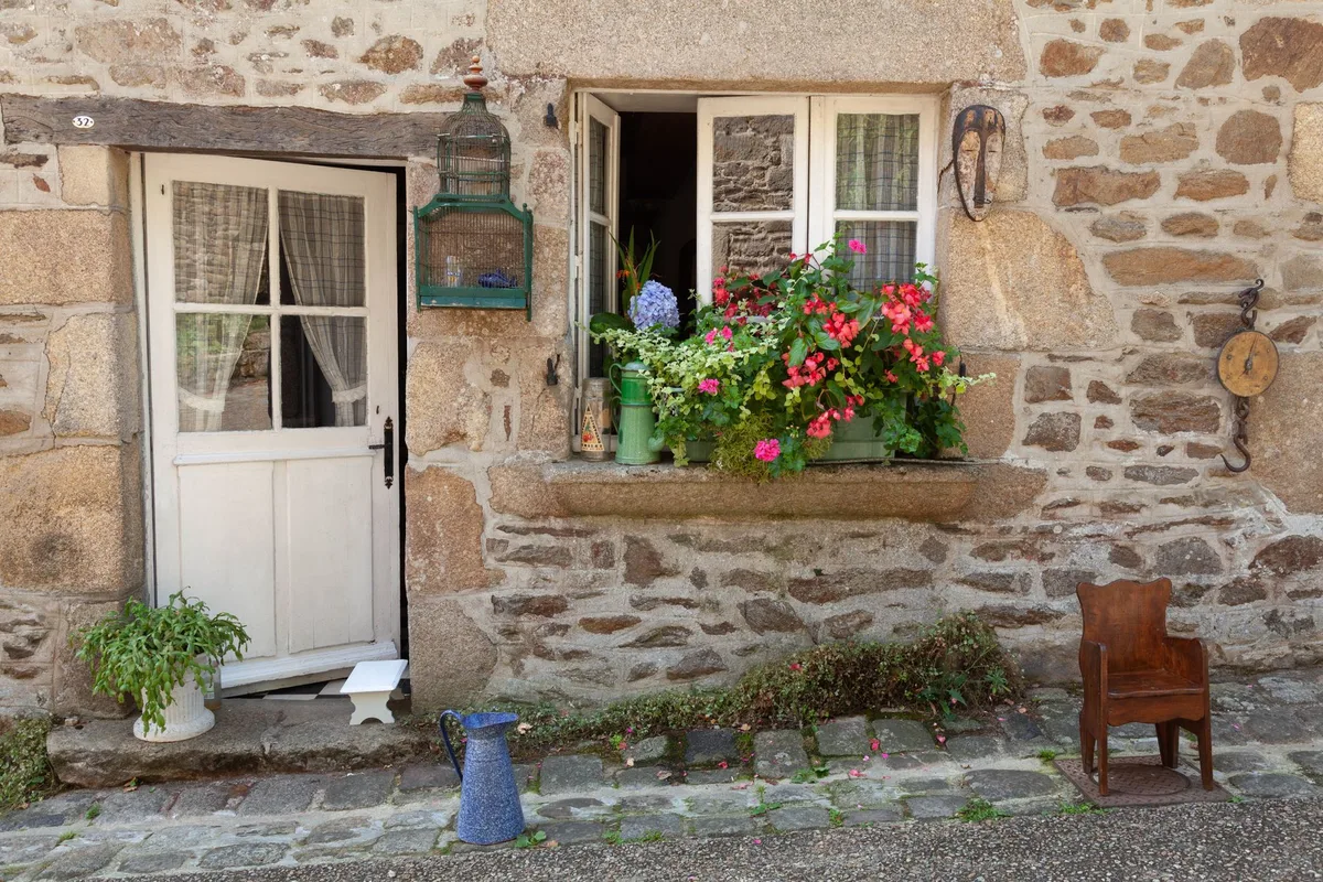 Maison ancienne bretonne en pierre avec fenêtre fleurie